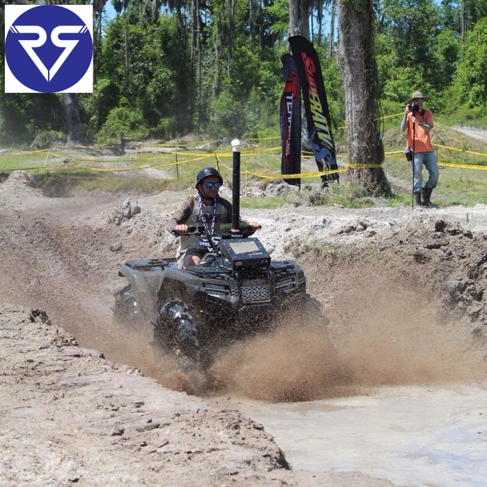 ATV rider splashing through muddy trail during off-road adventure race in forest terrain
