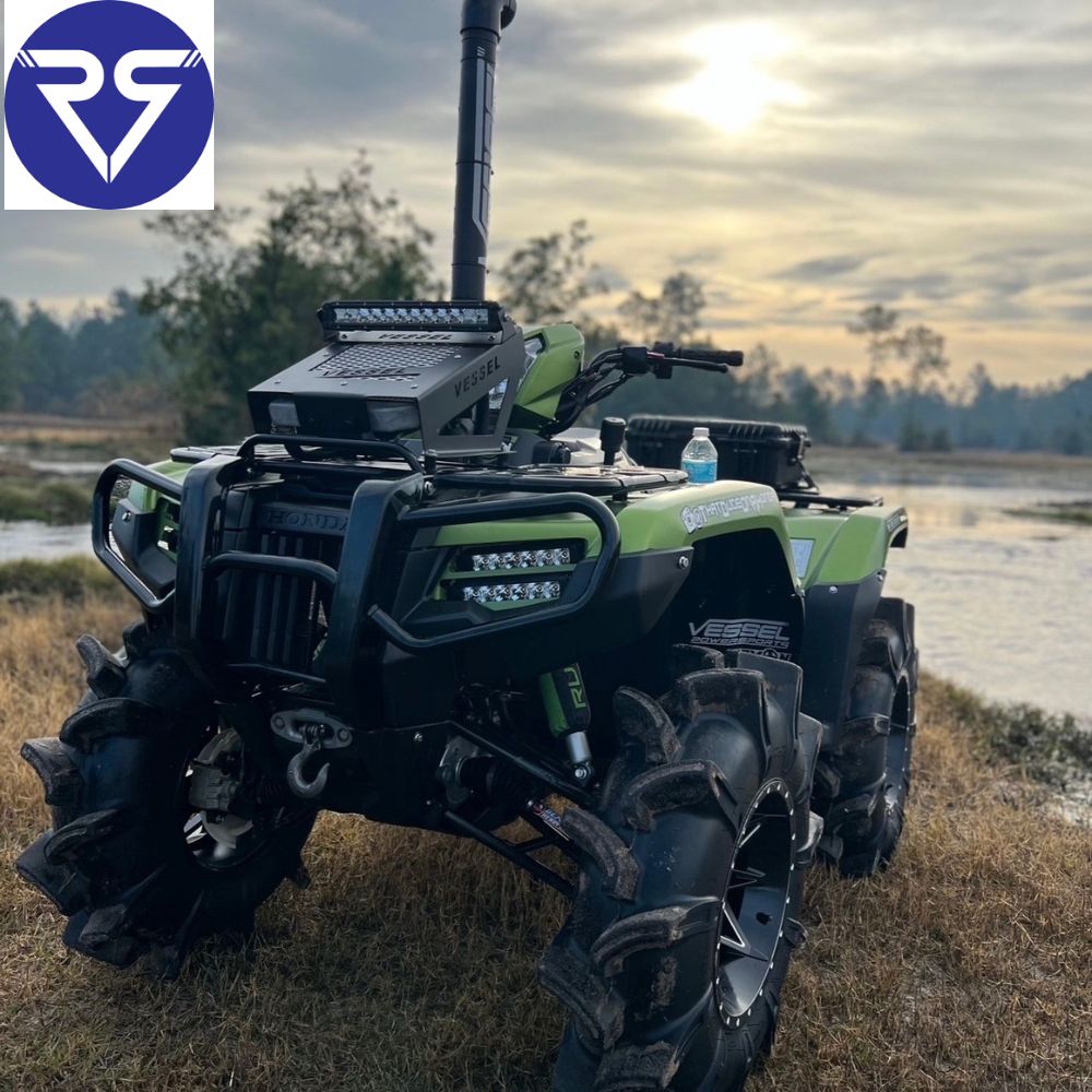 green ATv parked near a water body with cloudy weather in the background