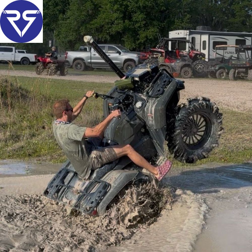 Rider performing a wheelie on a muddy ATV through a water crossing during an off-road adventure tour