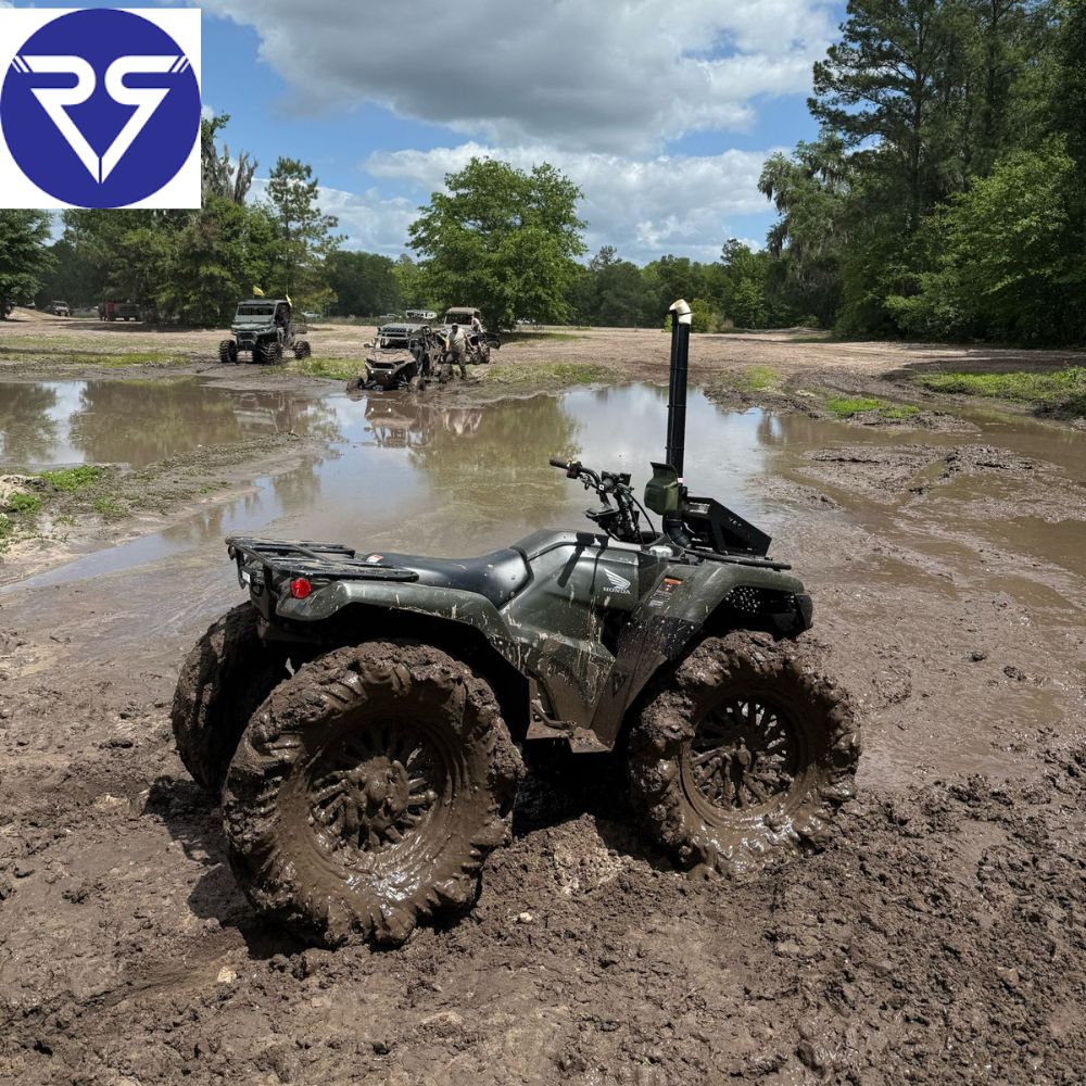 Honda ATV in mud with more ATVs in the background